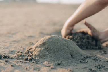 Seçici odaklanma, yaz kumsalında kumla oynayan çocukların elleri. Tatil kavramı