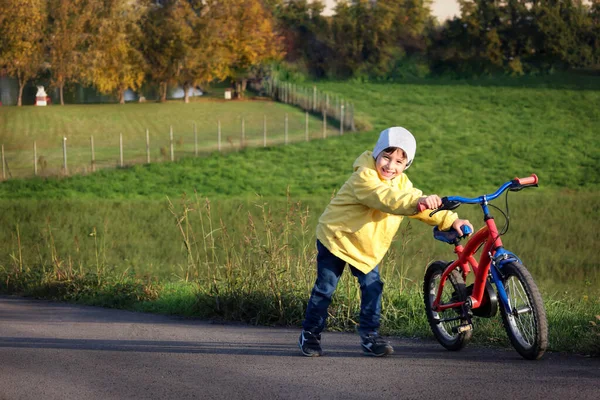 公園の道路を背景に自転車で黄色のジャケットの男の子 子供のサイクリング 屋外活動のための概念 外を歩く アクティブな健康的なライフスタイル 環境に優しい輸送コンセプト — ストック写真