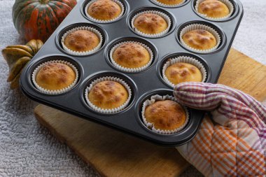 Kadın eli, ev yapımı balkabağı kekleriyle demir kalıbı tutuyor. Sonbahar tatlısı ve tarifler. Cadılar Bayramı hediyeleri. 