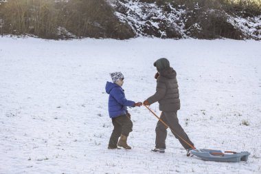Farklı yaşlarda iki erkek kardeş açık güneşli bir günde kızak kayıyor. Soğuk mevsim boyunca kış sporlarını, çocukluğu, boş zamanları ve aile eğlencelerini temsil eden kavram.