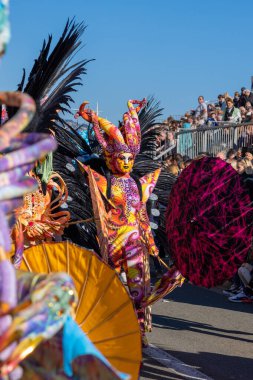 Menton, Fransa-12 Şubat 2023: Renkli fantastik bir karnaval kostümü giymiş ve büyük tüylü bir kadın geleneksel Limon Festivali karnavalında geçit töreninde. 