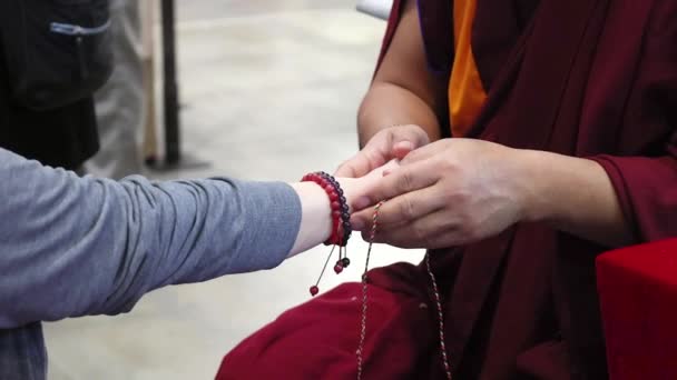 穿着传统服装的僧人正在另一人的手腕上绑着一根红色的绳子 它是僧人在文化或传统中具有特殊意义的宗教仪式 — 图库视频影像