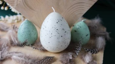 Ahşap arka planda Paskalya yumurtası ve tüyleri ve çiçek açan erik dalları. Paskalya konsepti