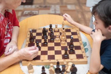 Seçici bir odaklanma ve bir büyükanne ve torununun satranç oyununa ve satranç tahtasına odaklanmış yakın plan görüntüsü. Uluslararası Satranç Günü.