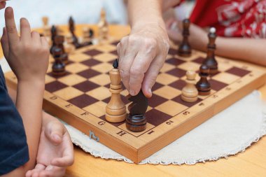 Büyükannesi torununa satranç hamlesi yapıyor sıcak ve ev ortamında öğrenmeyi ve stratejik düşünmeyi teşvik ediyor. Uluslararası Satranç Günü.