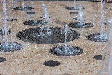 Asfaltlı yüzeyde kaynayan fıskiyelerle etkileşimli dairesel su kaynağı.