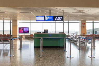 Milano, İtalya - 8 Mart 2025: Milan Malpensa Havalimanı 'ndaki güneşli terminalde oturma ve lcd ekranlı boş havaalanı kapısı a07.