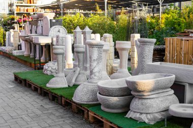 Bahçe merkezindeki bir perakende mağazasında suni çim bulunan paletlerde sergilenen çeşitli beton bahçe, açık hava dekorasyonu için geniş bir seçim sunuyor.