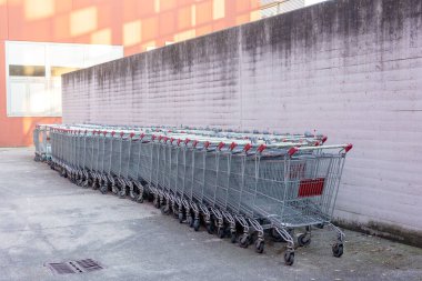 Piacenza, İtalya - 11 Mayıs 2025: Bir süpermarket duvarına dizilmiş boş alışveriş arabaları, alışverişçiler için düzenli ve davetkar bir atmosfer yaratıyor, perakende faaliyetlerine hazır hale getiriliyor