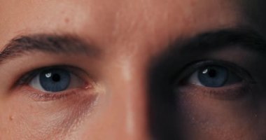 Makro yakın plan erkek güzel mavi gözler onları açıyor yavaşça kameraya ciddi ciddi bakıyor.