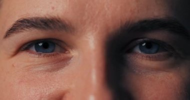 Makro yakın plan güzel mavi gözler mutlu bir şekilde gülümseyen bir adam, yüz kasları mutlu bakışlar.