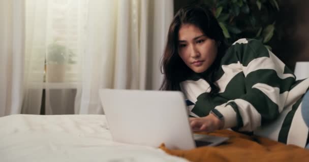一个女人躺在床上 带着一台电脑 在网上订购日用品 网站上的信用卡付款有所下降 女孩被取消了她的卡号弄糊涂了 — 图库视频影像