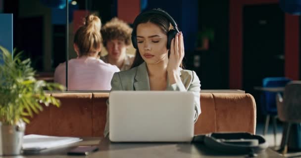 無線のイヤホンヘッドフォンの愛らしい若い女性は レストランのタイピングに座って音楽のリラックスを聞く仕事のための材料を準備インタビュー — ストック動画