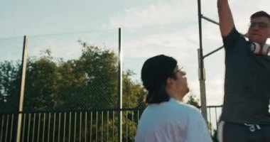 Men in sportswear playing basketball at playground score winning points doing slam dunk. Happy sunny day at weekends . Competition concept.