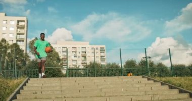 Slow motion focus on african american young man in sportswear holds basketball ball in hand runs to friends plays basketball with young team