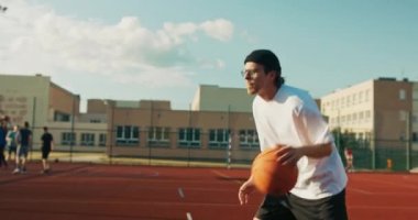 Modern stylish bestfriends basketball players spend time at weekends show skills training. Guy wears headphones listens to music while playing basketball. Sporty guys .