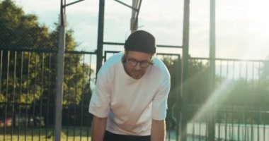 Handsome hipster in fashionable sportswear shows skills at camera stands at playground scores winniing points plays basketball with friends spends free time. Competition concept.