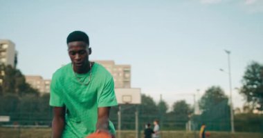 Seçici odaklı Afro-Amerikan erkek oyuncu kameradaki becerilerini gösteriyor. Oyun sahasında basketbol oynuyor ve smaç basmaya çalışıyor. Atış işlemi.