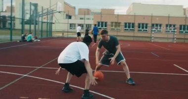 Concentrated friends playing basletball at playground man tries to make slam dunk competition time african american guy plays training shows skills .