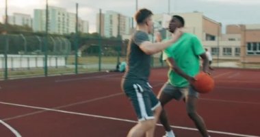 Competition time concentrated african american man playing basketball with friends at playground outside training friendship concept .
