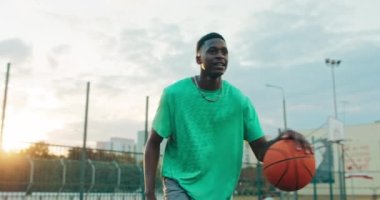 Yakışıklı afro amerikan erkeği spor giyim kuşamında şık stil basketbol oynuyor arkadaşlarıyla birlikte iyi bir ruh hali içinde zaman geçiriyor. Adam smaç basıyor..