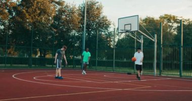 Happy friends company playing basketball outside african american player training guys outside at court. youth concept.