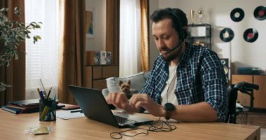 Tekerlekli sandalyedeki yakışıklı, orta yaşlı, sakallı adam. Engelli biri kulaklık takıyor. Evden internet üzerinden çalışan operatör müşteri destek yöneticisi .