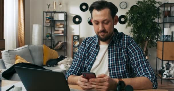 幸せなひげの男は仕事からの休憩中にオンラインで家族との通信メッセージをチャット手に携帯電話を保持しています 車椅子の障害者はオンラインで働いています フリーランスのコンセプト — ストック動画