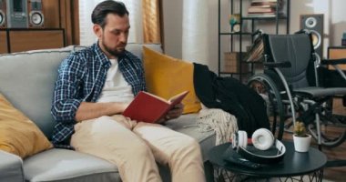 Kanepede oturan yakışıklı genç adam kitap okumayı bıraktı. Kulaklık ve cep telefonu aldı ve evde sıkı çalışma gününden sonra podcast dinledi. Whearcahir 'in yanında..