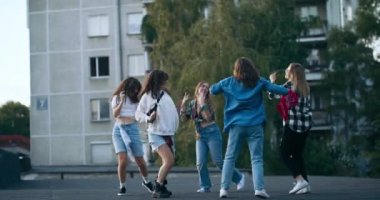 Shoolgirls şık kıyafetler giyip serbest stil hip-hop breakdance 'te yetenekler göstererek dışarıda eğleniyor ve okul arasında dinleniyor..