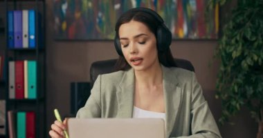 Ofis masasında oturan kafası karışmış genç bir kadın cep telefonuyla sohbet ediyor. .