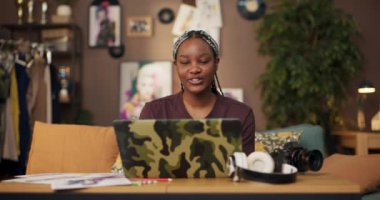 Afrikalı yetenekli moda tasarımcısı, bilgisayar kullanarak giyim markasını gösteriyor ve video görüşmeleri yoluyla potansiyel müşterilerle bağlantı kuruyor. Tasarımlarını sunuyor ve iş birliklerini tartışıyor..