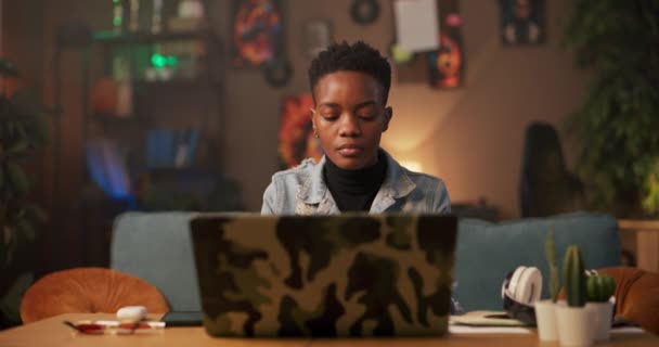 リモートワーカーやデジタル遊牧民アフリカの女性 彼女のリビングルームに座って 熱心に彼女のコンピュータ上で動作します 彼女のタスクに焦点を当て 彼女のラップトップをつかむと出て行く前に — ストック動画