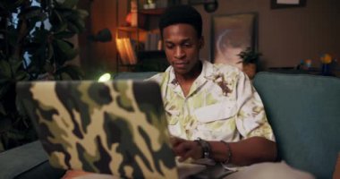 Afrika Çevrimiçi Dil Öğretmeni rahat koltuğa oturmuş Afrikalı adam, bilgisayar derslerini video konuşmalarıyla öğretiyor. Öğrencilerin dil bilgisini geliştirmesine yardımcı oluyor..