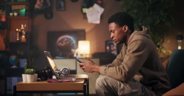 音楽プロデューサーアフリカ系アメリカ人男性がコンピューターとヘッドフォンで音楽を作る — ストック動画