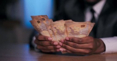 Yakın çekim Afrikalı eller yetenekli karaborsa tüccarı, ender ve değerli kaçak mallardan kazandığı dolarları sayarken kurnaz bir gülümseme sergiliyor..
