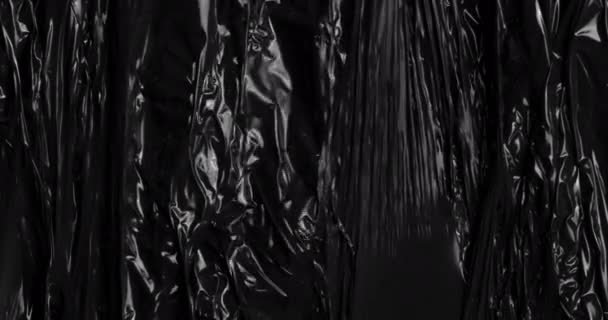 深入到一个迷人的世界中去 在黑色帆布上贴上有纹理的拉伸塑料膜 反映出与皱巴巴的玻璃纸包装类似的迷人褶皱和折痕 这些折皱和折皱通常用于包装食品 — 图库视频影像