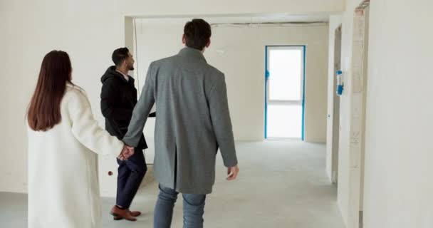 세일즈맨은 가족에게 지어진 아파트 투어를 제공합니다 부동산 에이전트는 객실을 커플이 — 비디오