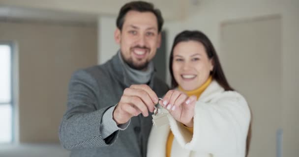 一对幸福的恋爱中的夫妻笑着看着摄像机 带着金块向房子展示钥匙 男人和女人一起拿钥匙 — 图库视频影像