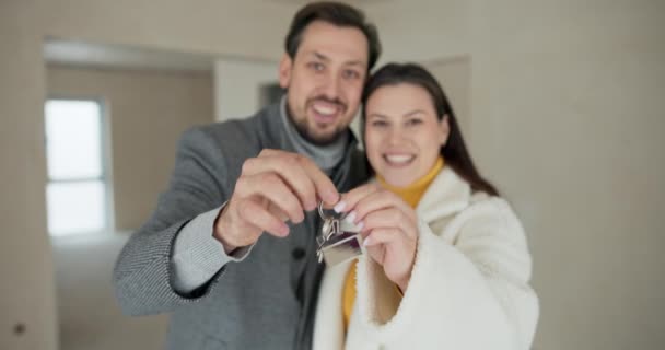 一对幸福的恋爱中的夫妻笑着看着摄像机 带着金块向房子展示钥匙 男人和女人一起拿钥匙 — 图库视频影像