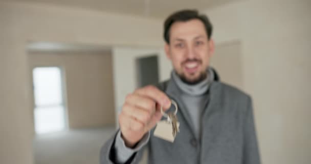 买公寓 从开发商那里买房子笑容满面的男人看着摄像机 拿出新财产的钥匙 — 图库视频影像