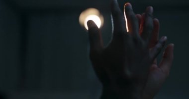 Beyaz kadın elleri ve dar derili erkekler el ele. Birbirlerine dokunuyorlar. Karanlık stüdyodaki parlak ışığa karşı dans ediyorlar. .