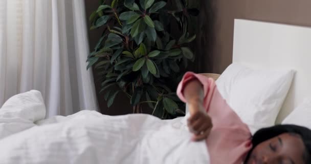 満足した女性を笑顔で目覚める ピンクのパジャマを着たキルトで覆われた少女は喜んで新しい日を始める — ストック動画