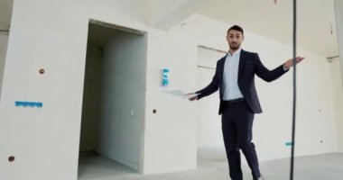 Emlakçı, müşterilere modern binaları gösteriyor. Mutlu erkek kırsal kesimde yeni bir bina satmak istiyor. Yenileme yapılmadan inşa ediliyor.