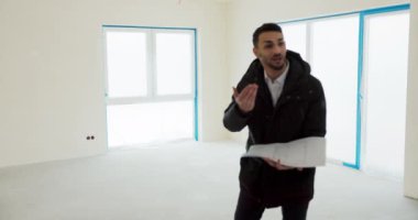 Erkek emlakçı, mutlu ve genç aileye yeni bir ev gösteriyor..