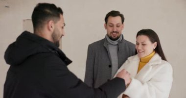 Happy couple buying their new home and receiving keys from real estate agent.