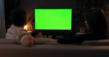 Yeşil ekran model televizyon. Omzundan vurulan iki kadın arkadaş oturma odasında oturmuş televizyon filmleri izliyorlar. Hafta sonu mesai saatinden sonra birlikte zaman geçiriyorlar..