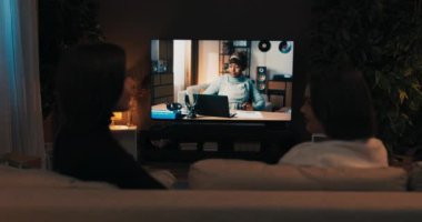 Omzundan vurulmuş. Akşamları iki arkadaş oturma odasında oturup son haberleri tartışıyor ve TV 'de film seyrediyor..