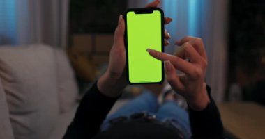 Kanepede uzanan bir kadın elinde cep telefonu, elinde akıllı bir telefonla film seyrediyor. İnternetteki görüntülerde geziniyor. Toprak ağlarında geziniyor, hareketler yapıyor. Bakış açısı.