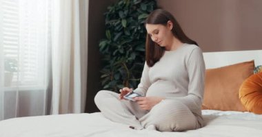 Çekici hayalperest kadın ultrason görüntülerini tutarken gülümsüyor, onlar gelmeden bebeğiyle olan sevgisini ve bağlantısını hissediyor. Anneler Konsepti.